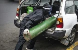 Un homme charge dans une voiture une bouteille d'oxyène vide pour aller la remplir, le 3 juin 2020 à Lima, au Pérou