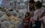 Une femme et ses enfants regardent des poupées "reborn" exposées au magasin Maternité Alana Babys à Campinas, dans l'État de Sao Paulo, au Brésil, le 16 mai 2025