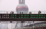 Des gens marchent sur un pont avec un écran montrant les cotations boursières à Shanghai le 7 janvier 2016