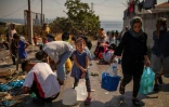 Une fillette attend son tour pour remplir des bidons d'eau le 16 septembre 2020 après avoir été jetée à la rue par l'incendie du camp de Moria