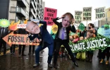 Des militants pour le climat ont revêtu des masques représentant le Premier ministre britannique Boris Johnson (d) et le président américain Joe Biden lors d'une manifestation anti-énergies fossiles à Glasgow, en Ecosse, le 12 novembre 2021
