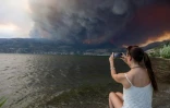 Une habitante observe la fumée des feux qui menacent la ville de West Kelowna, dans la province canadienne de la Colombie-Britannique, le 17 août 2023