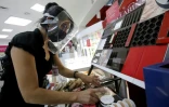 Une vendeuse équipée d'une visière et d'un masque de protection dans une boutique de cosmétiques, le 1er juin 2020 à Guadalajara, au Mexique