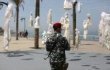 Un policier lmibanais devant l'installation de robes de mariée accrochées sur des palmiers à Beyrouth  dans le cadre d'une campagne pour abolir une loi qui permet à un violeur d'échapper à la prison s'il épouse sa victime, le 22 avril 2017