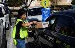 Une employée livre les commandes à des automobilistes en drive-in sur le parking d'un magasin, pendant le Black Friday, le 27 novembre 2020 à Hawthorne, en Californie