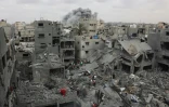 Des secouristes  palestiniens inspectent site d'un bombardement israélien sur un immeuble résidentiel dans le quartier de Choujaïya à Gaza-ville, avec en arrière-plan un nuage de fumée, le 9 avril 2025