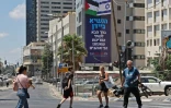 Un panneau du groupe anticolonisation israélien La Paix Maintenant, surmonté des drapeaux palestinien et israélien, à Tel-Aviv le 11 juillet 2022