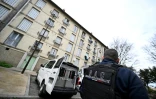 Un policier de la brigade anticriminalité contrôle devant un bâtiment utilisé par des trafiquants présumés dans un quartier d'Avignon, le 13 mars 2025