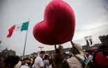 Un homme avec un ballon en forme de coeur rouge attend le "cri" de l'Indépendance sur la place du Zocalo à Mexico, dimanche 15 septembre 2024, jour de fête nationale au Mexique