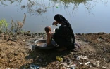 Une femme déplacée en raison des inondations lave son enfant dans un campement de fortune à Mehar dans la province du Sind au Pakistan, le 9 septembre 2022