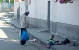 Un homme essaie d'aider une femme âgée qui a reçu une balle dans le pied, à Port-au-Prince, Haïti, le 9 mars 2024