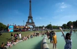 Des gens se rafraîchissent dans une fontaine au pied de la Tour Eiffel le 2 août 2018 à Paris