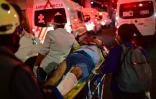 Des ambulanciers évacuent un blessé après l'effondrement d'un pont du métro aérien au passage d'une rame, le 3 mai 2021 à Mexico