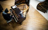 Un bénévole essaie un piano dans l'atelier "Pianodrome", le 9 février 2023 à Edimbourg, en Ecosse