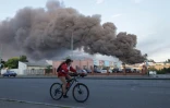 Une femme sur un vélo passe devant un entrepôt visé par une frappe russe à Odessa, le 16 juillet 2022 