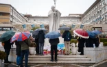 Des personnes prient devant la statue de Jean-Paul II à l'extérieur de l'hôpital Gemelli à Rome, où est hospitalisé le pape François, le 1er mars 2025