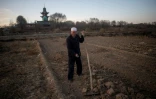 Un Chinois musulman travaille dans son champ, une mosquée en arriÚre-plan, le 2 mars 2018 prÚs de Linxia, dans le nord-ouest de la Chine