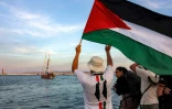 Un homme agite un drapeau palestinien à l'adresse d'activistes se trouvant dans un bateau quittant le port tunisien de Bizerte pour Gaza, le 14 septembre 2025