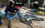 Un migrant assis sur un matelas dans un camp sous la station de métro Stalingrad à Paris le 24 mars 2016