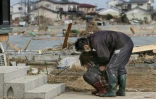Une habitante de Watari, dans le nord-est du Japon, s'effondre en larmes devant sa maison détruite par le séisme et le tsunami, le 14 mars 2011