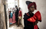 Des jeunes filles regardent un mannequin travaillant avec la créatrice de mode, Ndeye Diop Guisse, en tenue traditionnelle des Signares à Saint Louis, le 10 août 2021