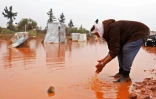 Abou Khaled se lave les mains dans une flaque d'eau boueuse formée par les fortes pluie dans un camp de fortune de déplacés à Batabou, à la frontière entre les provinces syriennes d'Idleb et d'Alep, le 24 janvier 2018