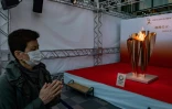 La flamme olympique, sous le regard d'un Japonais portant un masque, lors de son passage à Sendai, au nord du Japon, le 21 mars 2020