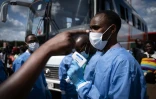 Un membre du Centre biomédical du Rwanda prend la température des passagers à un gare routière à Kigali, le 22 mars 2020