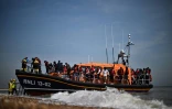 Des migrants récupérés en mer par un navire de la Royal National Lifeboat Institution (RNLI) alors qu'ils tentaient de traverser La Manche, débarquent sur une plage de Dungeness, le 15 juin 2022 au sud-est de l'Angleterre