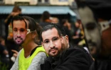 Des manifestants portant des masques à l'effigie d'Alexandre Benalla sont rassemblés le 1er mai 2019 sur la place de la Contrescarpe à Paris