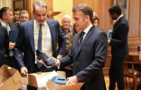 Le président français Emmanuel Macron (D) reçoit des mains du Premier ministre grec Kyriakos Mitsotakis une paire de baskets fabriquées en Grèce à l'issue d'un déjeuner  Athènes, le 25 avril 2026 à Athènes 