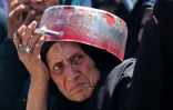 Une Palestinienne fait la queue pour recevoir un repas chaud à un point de distribution de nourriture dans le camp de réfugiés de Nousseirat, dans le centre de la bande de Gaza, le 24 mai 2025