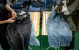 Des employés vérifient des jeans d'occasion dans un entrepôt de la ville d'Inashiki, dans la préfecture d'Ibaraki, le 31 octobre 2023 au Japon