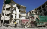 Un Casque blanc syrien devant un immeuble détruit par une frappe aérienne du régime de Damas, le 12 juillet 2019 à Idleb