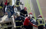 Des secouristes transportent le corps d'une victime dans les décombres d'un immeuble résidentiel touché par des frappes de drones et de missiles russes à Kiev, le 14 mai 2026 en Ukraine