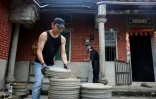 Un employé de l'Institut taïwanais du cinéma et de l'audiovisuel (TFAI) empile des bobines de vieux films taïwanais à restaurer issus d'une collection privée, le 29 mai 2026 à Changhua, dans la province de Taïwan

