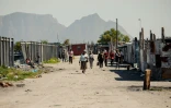 Vue d'habitants du site de Blikkiesdorp - "Boîte de conserve-ville" en afrikaans -, rangées de cahutes alignées sur un terrain désolé près de l'aéroport international du Cap, le 19 août 2024, en Afrique du Sud. 