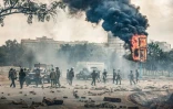 Des membres des forces de sécurité près d'un panneau publicitaire en feu après des heurts avc des manifestants lors des commémorations du premier anniversaire de la prise du Parlement, le 25 juin 2025 à Nairobi, au Kenya