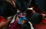 Des enfants de la tribu Waiapi regardent sur un smartphone une vidéo d'une danse traditionnelle Waiapi, dans leur village de Manilha le 12 octobre 2017