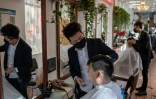 Des coiffeurs portent un masque de protection dans un salon de Pékin le 23 janvier 2020
