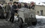Des mineurs poussent un wagonnet rempli de minerai à trier dans une mine d'émeraude de la vallée de Mikeni au Panchir afghan, le 12 janvier 2022 