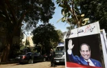 Photo montrant une pancarte à l'effigie d'Abdel Fattah al-Sissi et un policier gardant l'entrée d'un bureau de vote, lors du premier jour de la présidentielle, le 26 mars 2018 à Zamalek, dans le centre du Caire