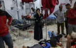 Une Palestinienne au milieu de personnes blessées par des tirs israéliens à un point de distribution d'aide alimentaire de la Fondation humanitaire de Gaza (GHF), prises en charge à l'hôpital Al-Awda du camp de réfugiés de Nousseirat, dans le centre de la bande de Gaza, le 24 juin 2025