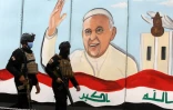 Des forces de sécurité irakiennes devant une fresque murale représentant le pape François, le 4 mars 2021 à Bagdad