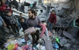 Un Palestinien porte le corps d'une enfant, sortie des décombres, après une frappe dans la ville de Gaza le 30 décembre 2023