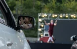 Un artiste se produit lors d'une représentation de cirque en drive-in devant des automobilistes à Séoul, le 19 septembre 2020