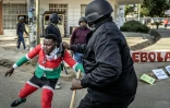 Un manifestant arrêté par un policier lors d'une manifestation contre un centre de quarantaine Ebola construit par les États-Unis sur la base aérienne de Laikipia, le 9 juin 2026 à Nanyuki, au Kenya