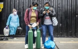 Deux femmes attendent une voiture pour aller remplir des bouteilles d'oxygène vides, le 3 juin 2020 à Lima, au Pérou