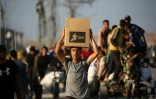 Des Palestiniens marchent le long d'une route de retour d'un point de distribution d'aide de la Fondation humanitaire de Gaza (GHF,) près du camp de réfugiés de Nousseirat, dans le centre de la bande de Gaza, le 25 juin 2025