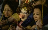 L'actrice hongkongaise Lana Wong (au centre avec un groin de porc) se presse entre deux femmes devant un temple pour fêter le Nouvel An chinois ouvrant l'année du "cochon de terre", le 4 février 2019 à Hong Kong